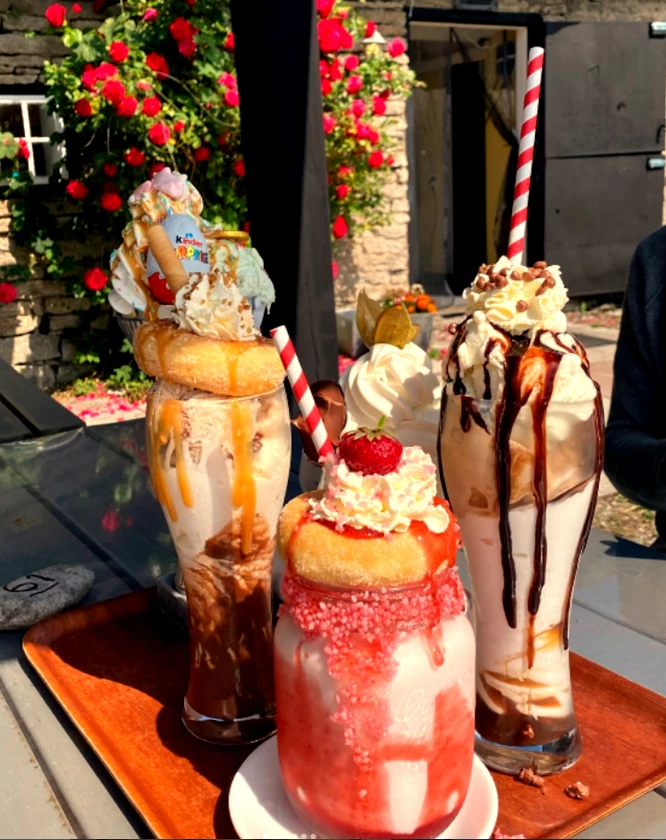 Tre milkshakes på bricka framför rosor