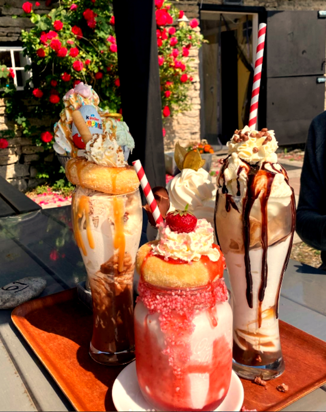 Tre milkshakes på bricka framför rosor